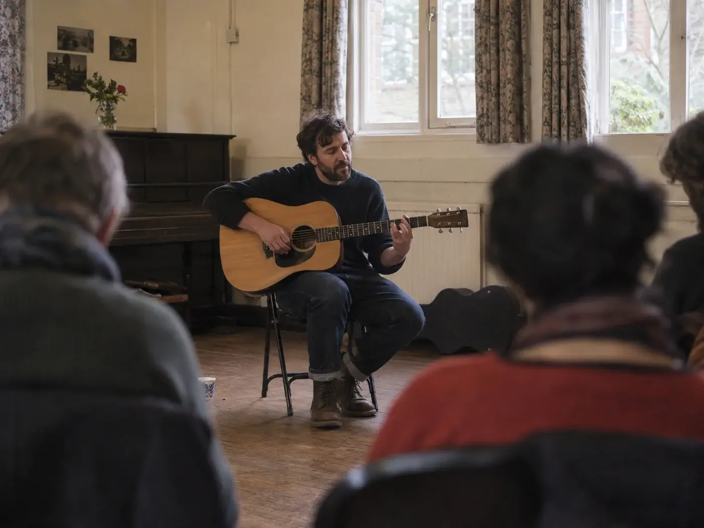 An acoustic musician playing to a small seated audience.
